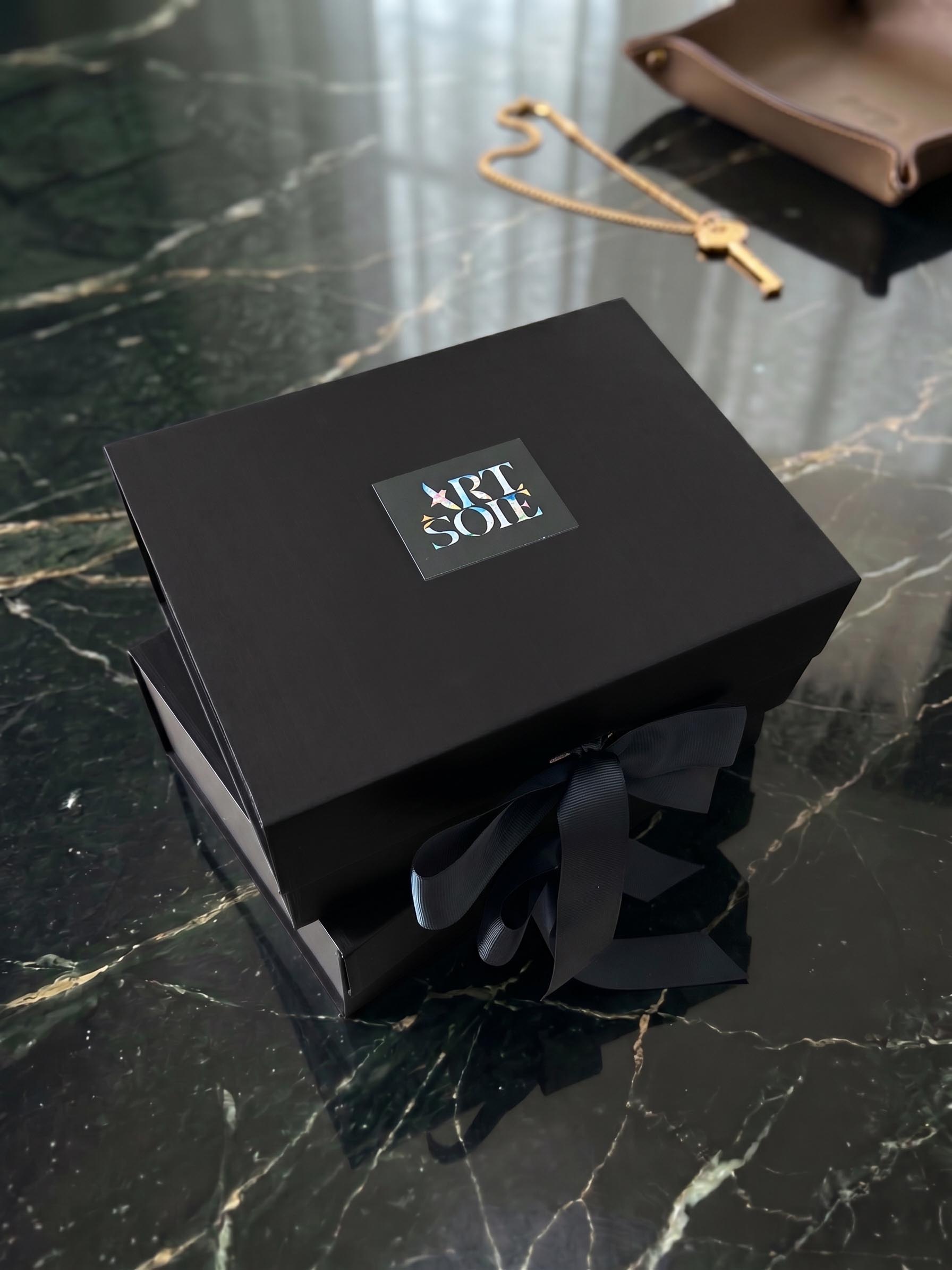 A silk artwork presentation box beside a prepared surface for handling and wall-display planning